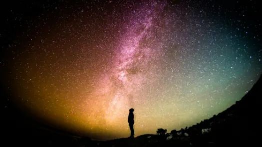 Image of a silhouette of a man stood with a universe behind him